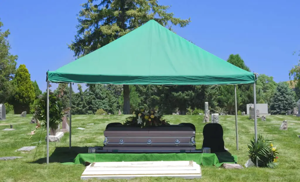 Image of a steel Casket with Flowers on top in a cemetery